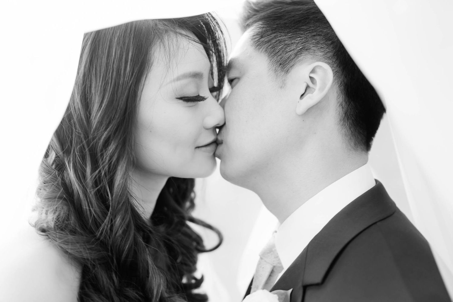 Romantic black and white portrait of a couple sharing an intimate kiss.