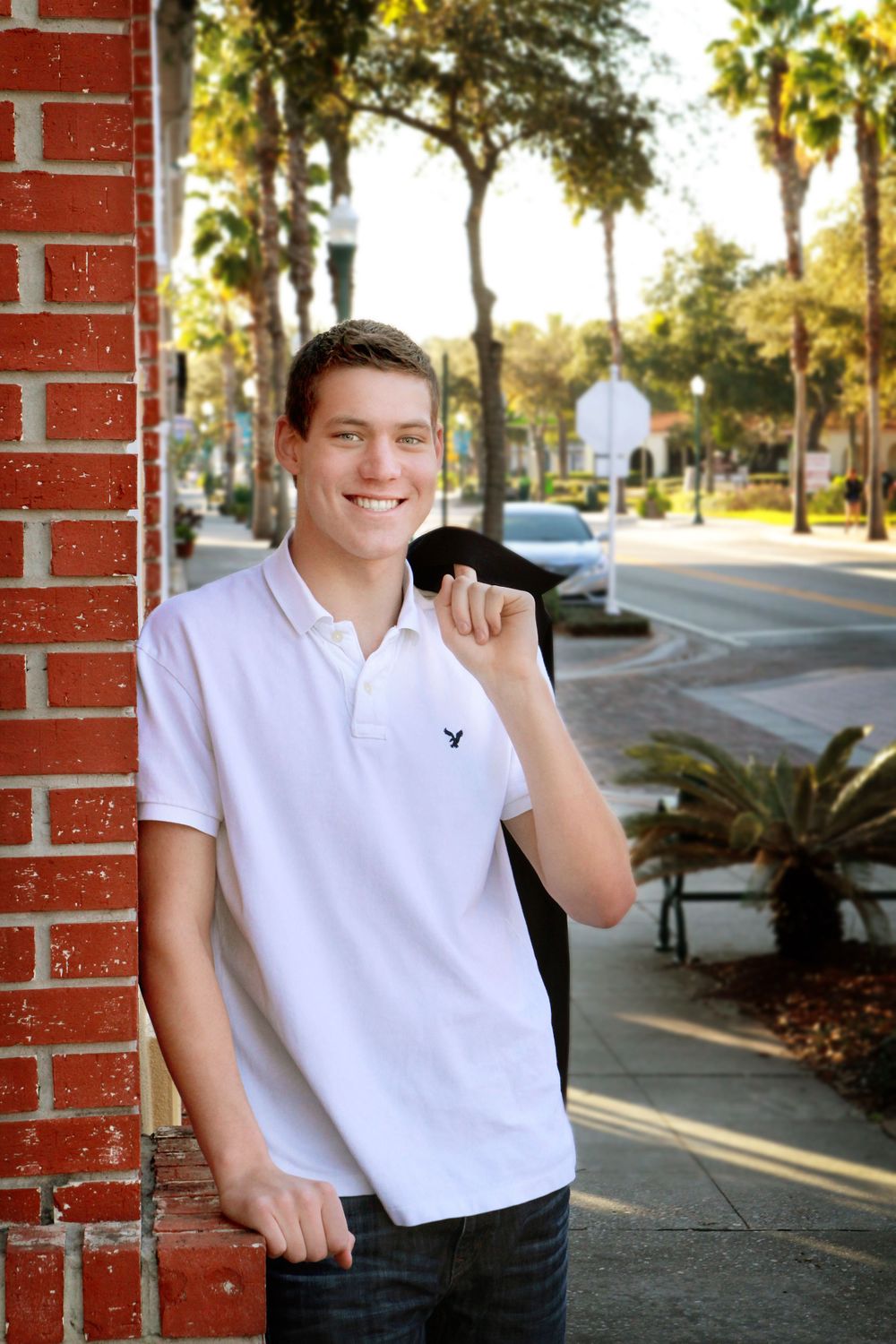Young man in white shirt leaning against a brick building in Safety Harbor.