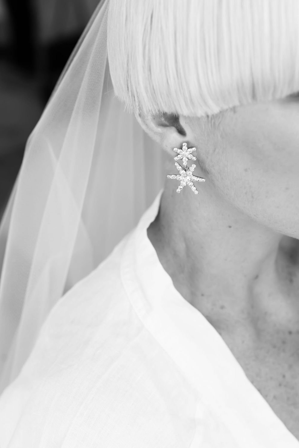 Close-up of an elegant starfish-shaped wedding earring with veil detail.