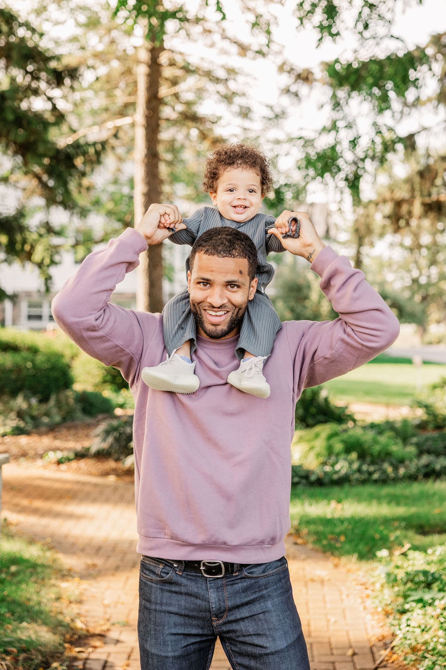 A playful moment captured with a child riding on shoulders in a park setting.