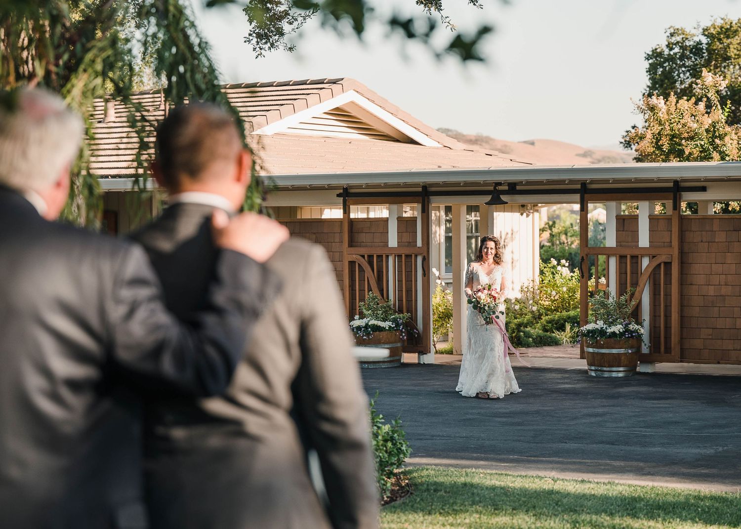 A wedding first look moment outside a brick building with a white dress in view.