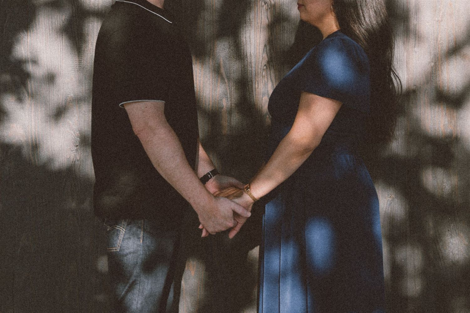 Silhouetted figures hold hands in dappled light and shadow.