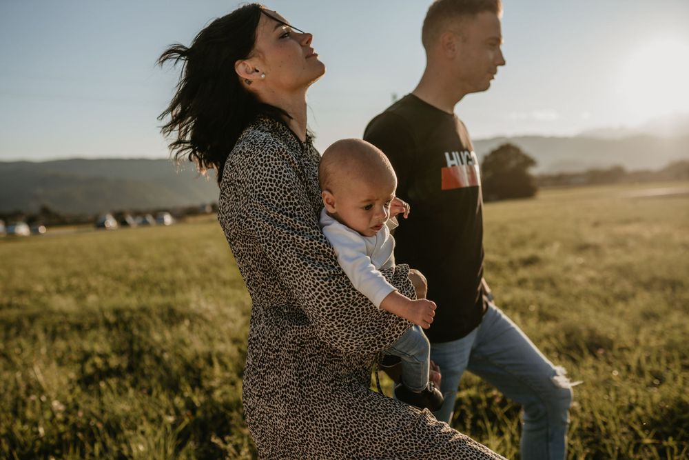A candid family moment captured in a sunlit meadow during sunset.