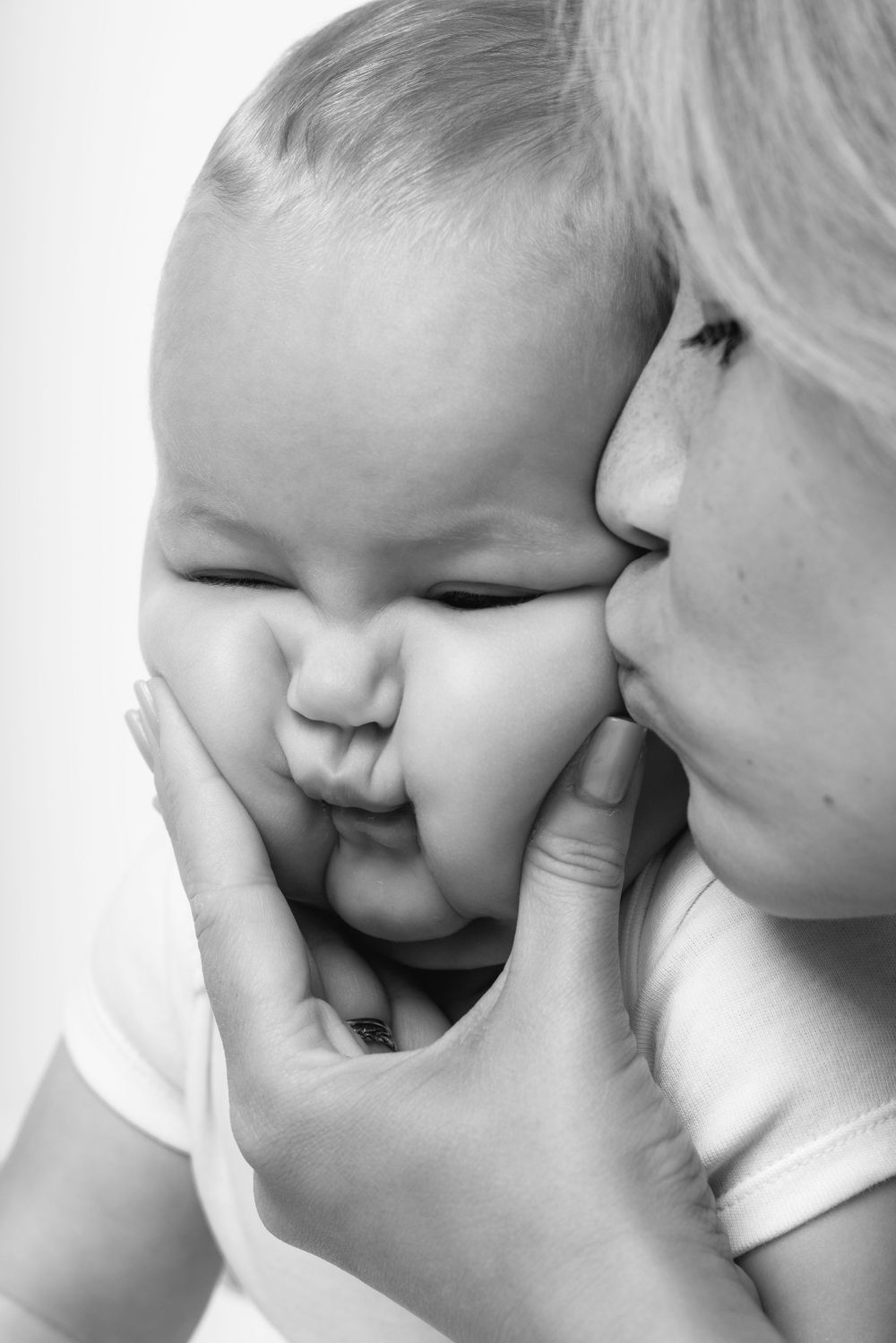 A tender black and white moment capturing a gentle kiss and smile.