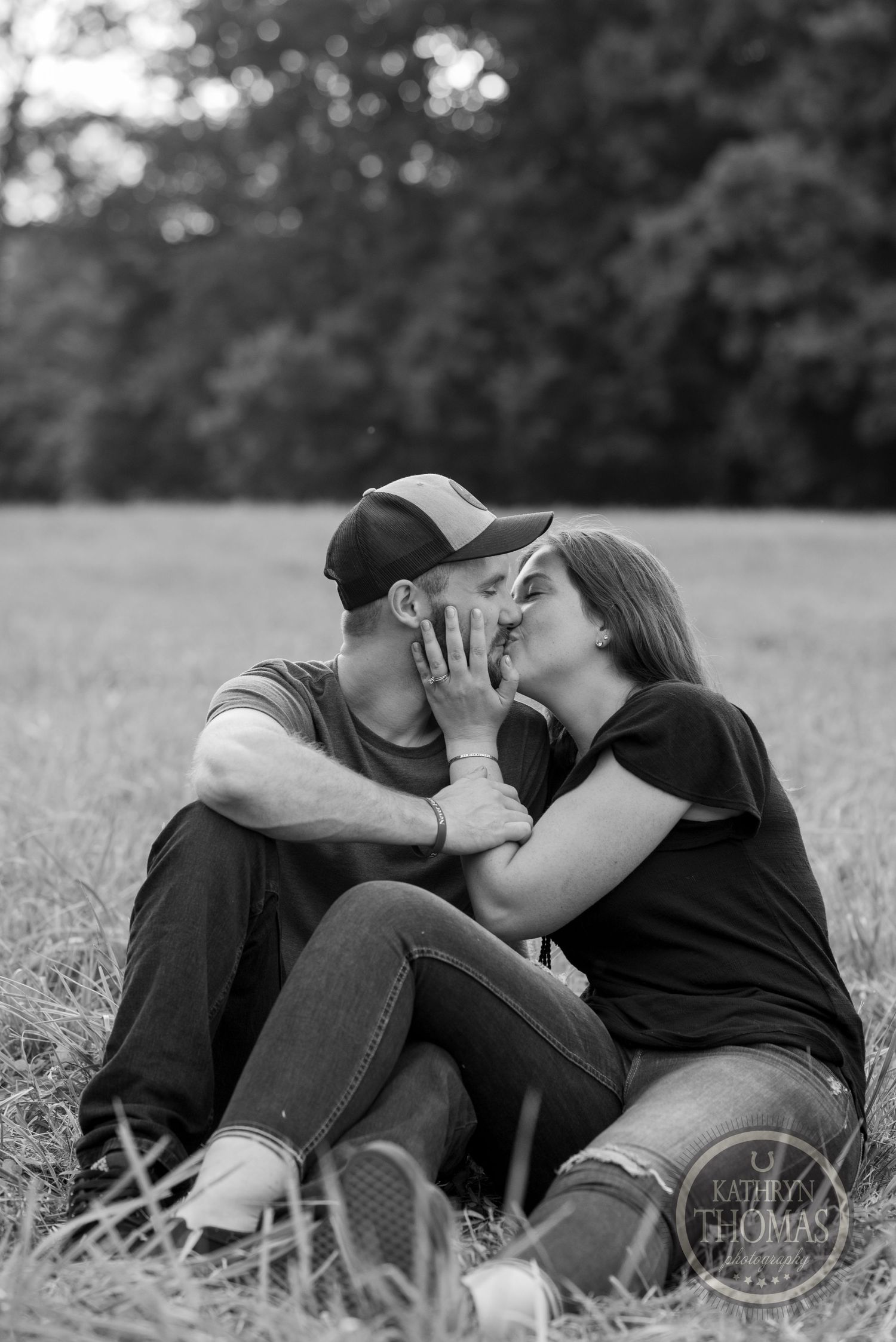 Intimate black and white portrait of couple sharing tender moment in field.