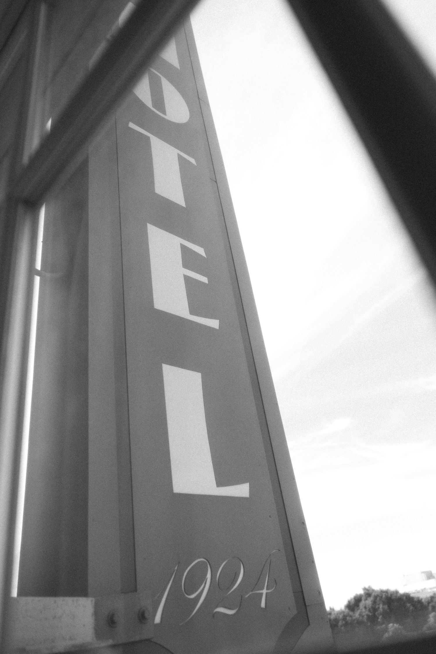 Black and white architectural detail showing hotel signage from 1924 photographed from a low angle against bright sky.