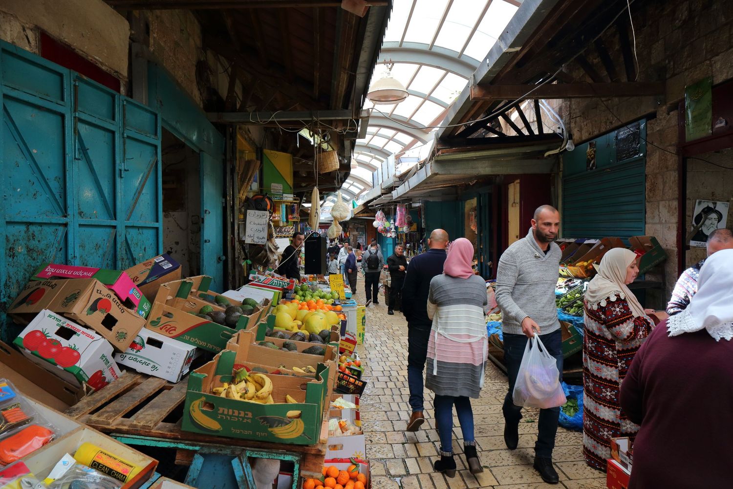 Busy market scene in Middle Eastern bazaar with vendors selling fresh produce and goods.