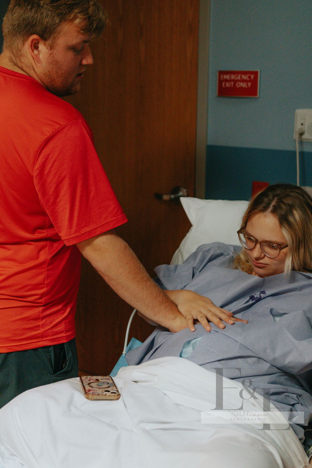 Medical staff in red scrubs attending to a patient in a hospital bed.