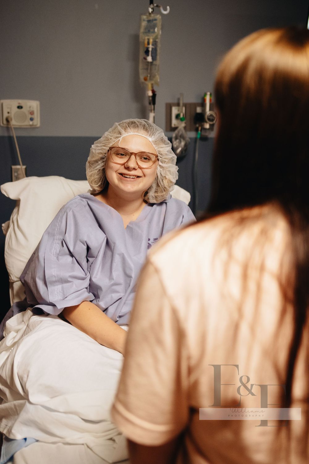 Patient wearing glasses rests comfortably in a hospital bed while receiving care.
