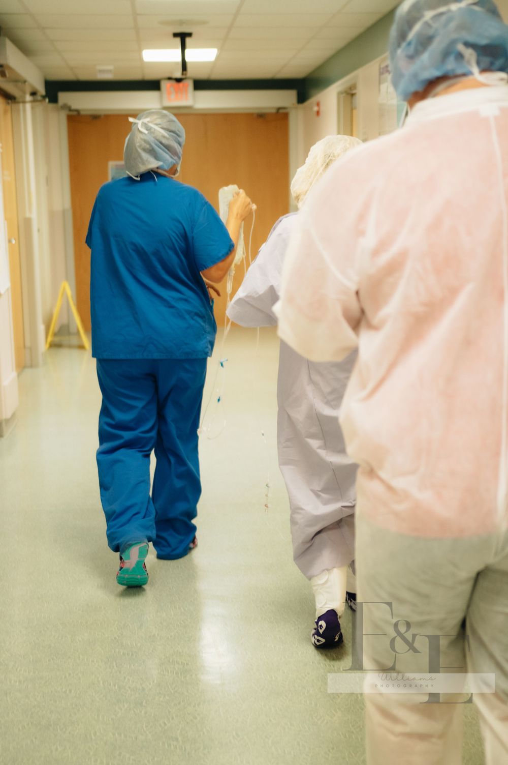 Medical professionals in blue and white scrubs walking down a hospital hallway.
