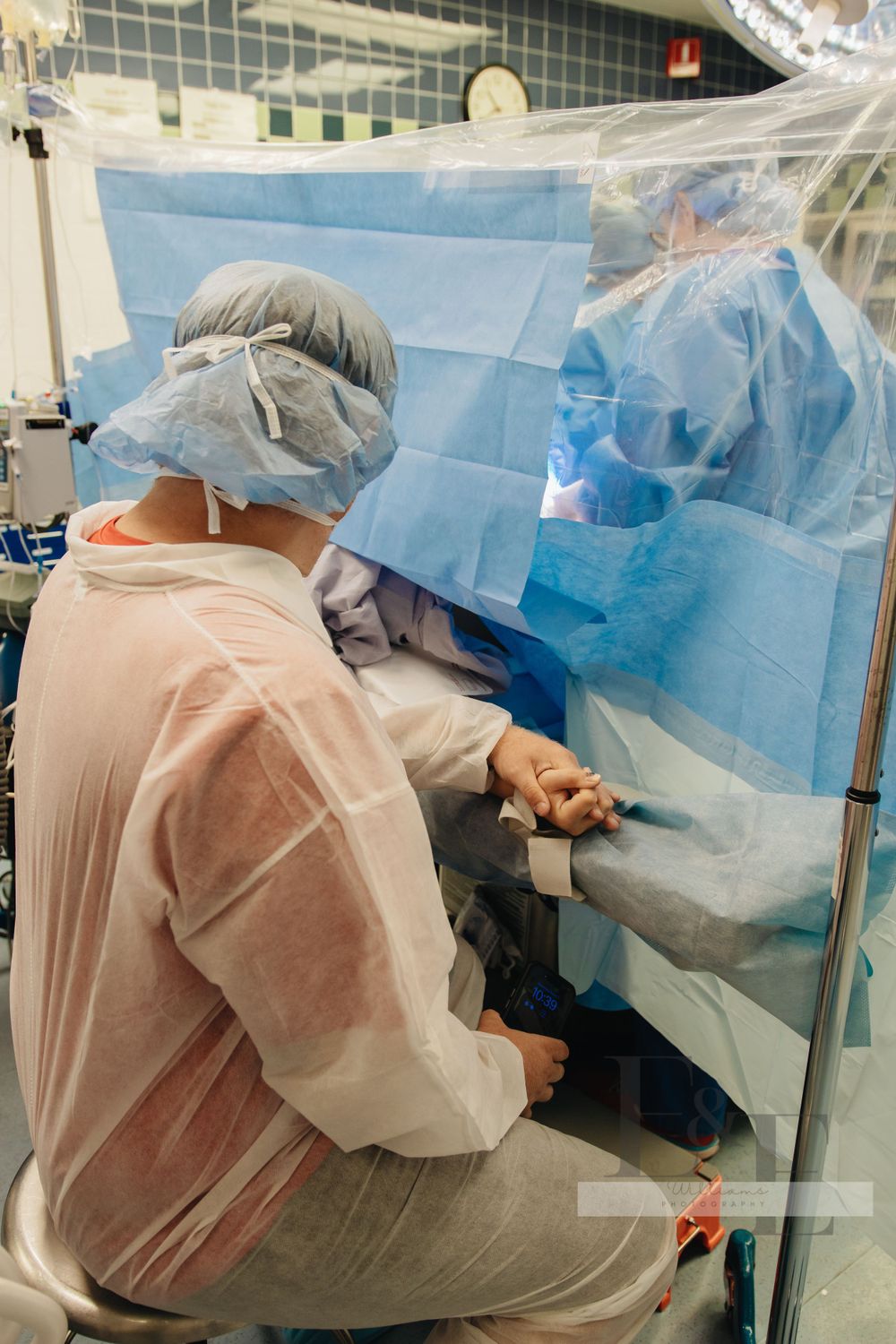 Medical team performing surgery with blue surgical drapes visible.