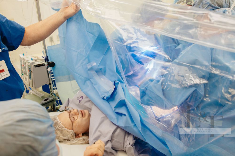 Surgical procedure in progress with blue medical drapes and equipment visible.