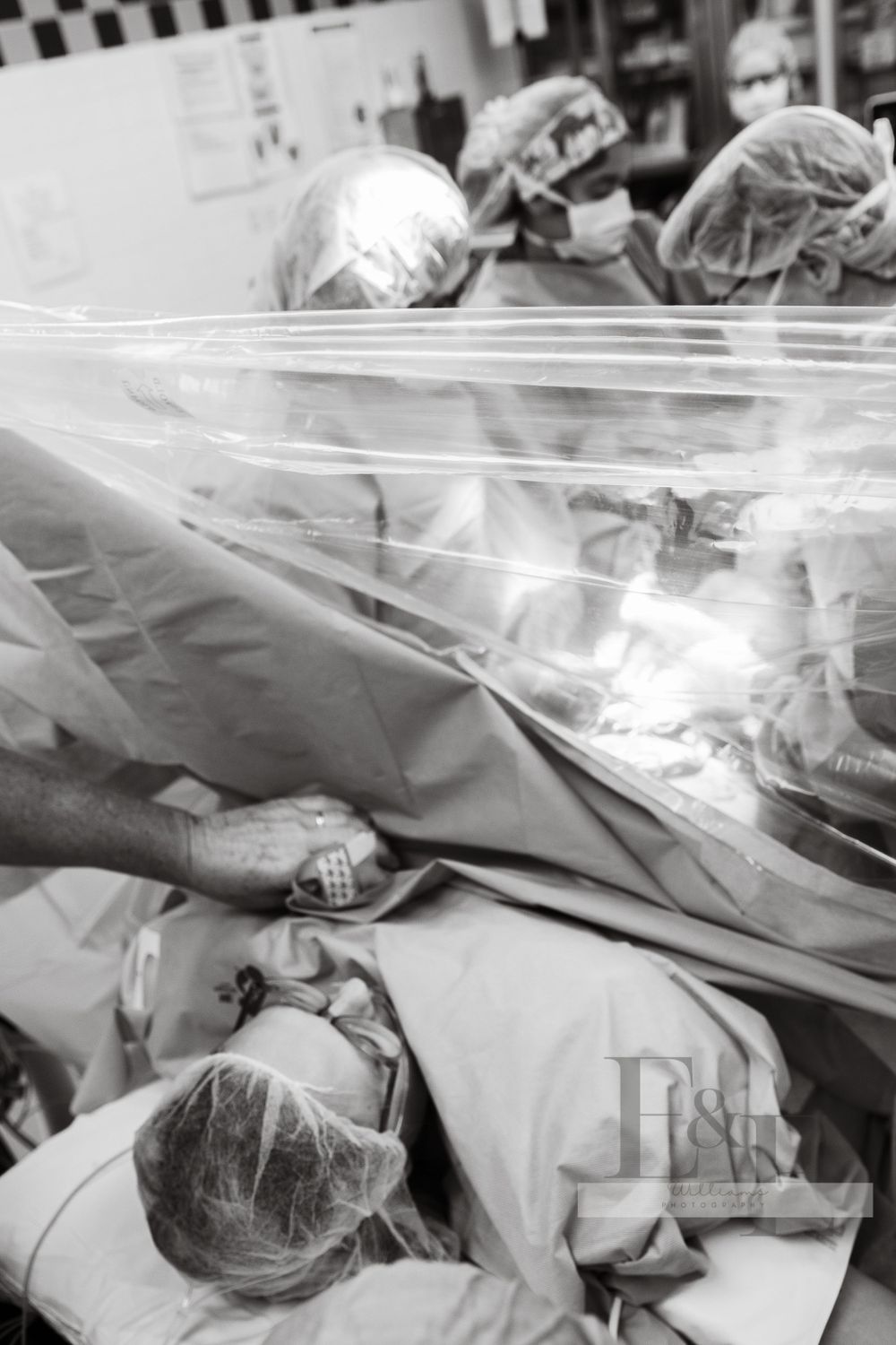 Medical team performing surgery in an operating room with surgical drapes and equipment.