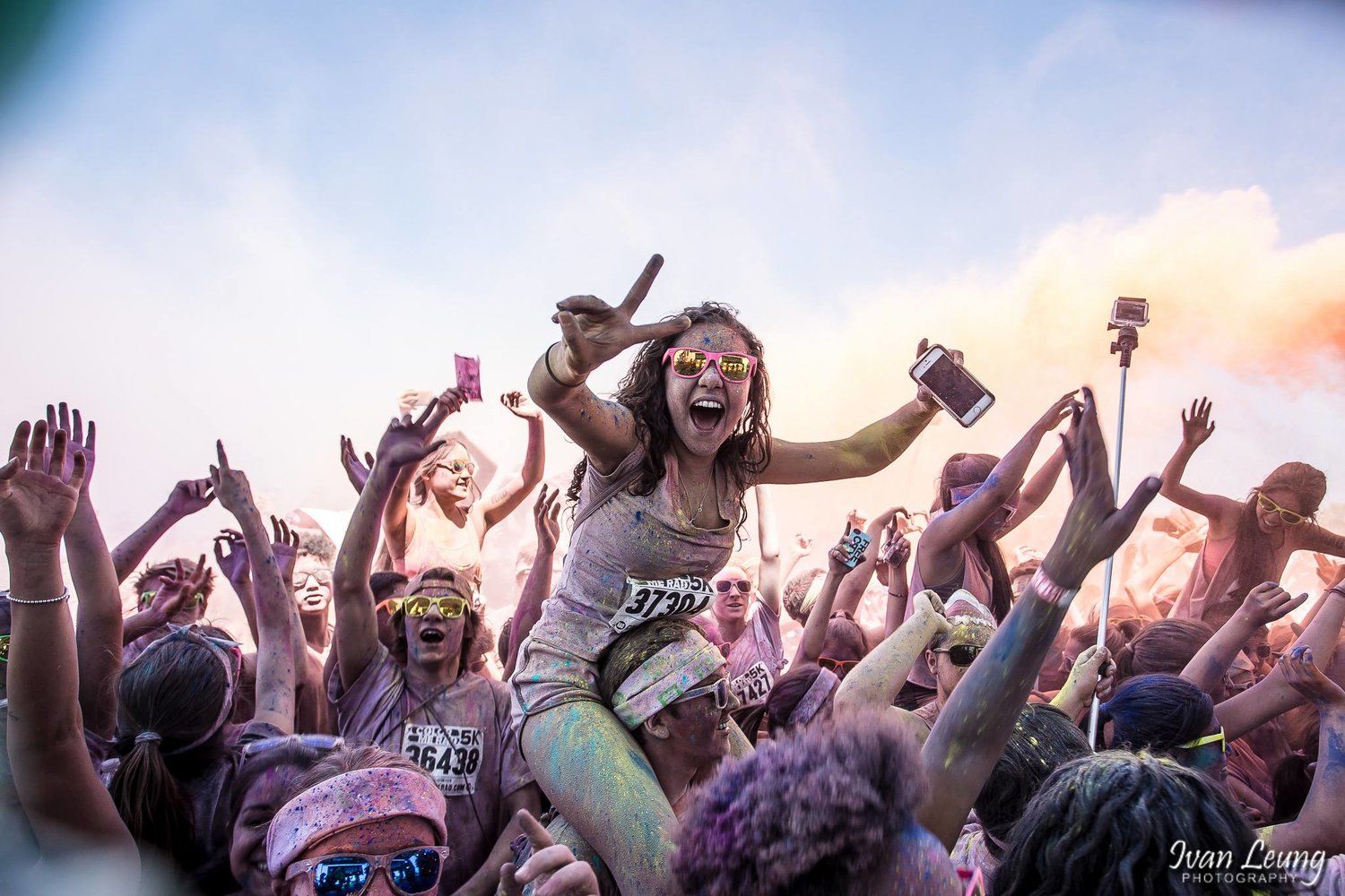 Girl riding on a shoulder waving the peace sign at a Colour Me Rad event at Downsview Park