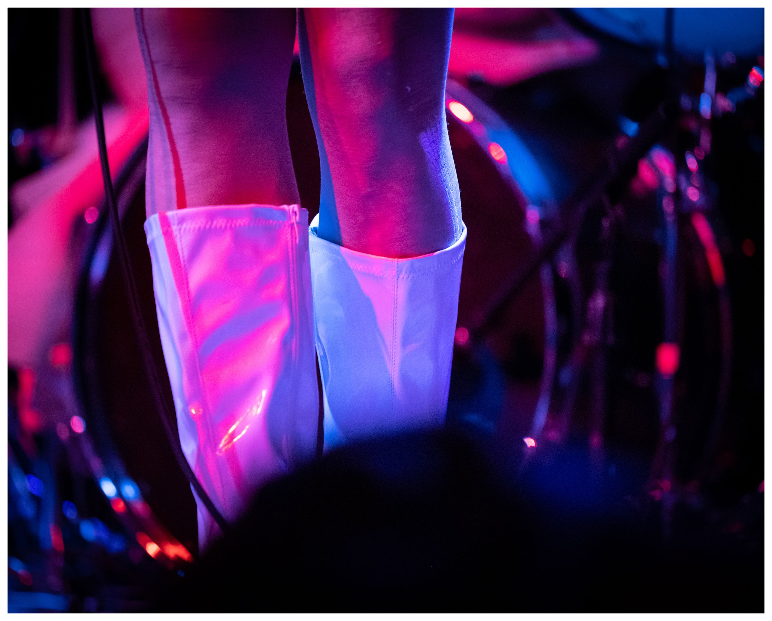 Close-up of white platform boots on a performer under colorful stage lighting at a live concert.