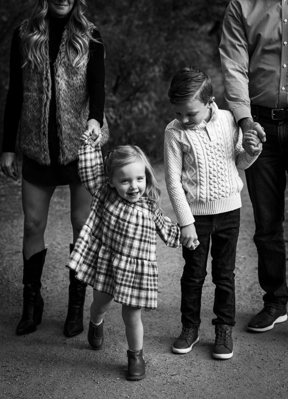 A family holds hands while walking, with children wearing cozy winter sweaters.