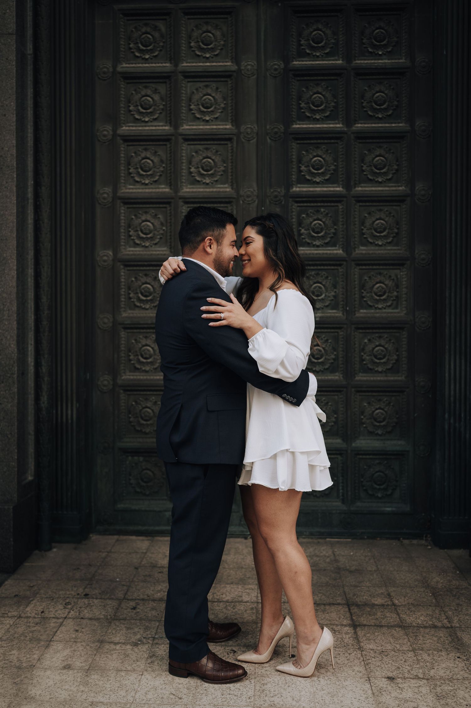 Houston area couple's engagement session. She is wearing white and red-bottom shoes. He is wearing a navy suit.