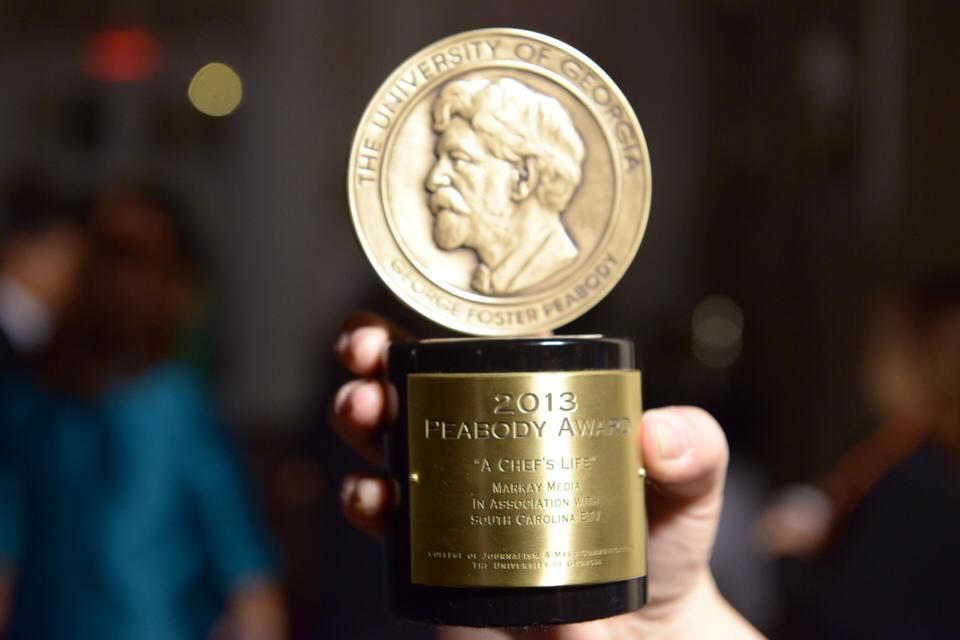 A gold James Beard Award trophy statue displayed against a dark background with bokeh lights.