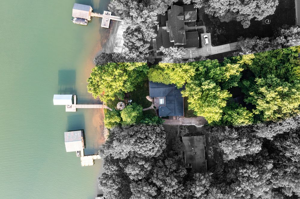 Aerial view of docks and boats on a green lake surrounded by trees and shoreline.