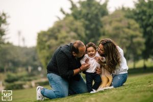 Family sharing playful moment together on grass in park setting.