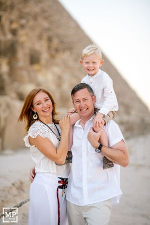 A happy family poses together near the ancient pyramids in Egypt.