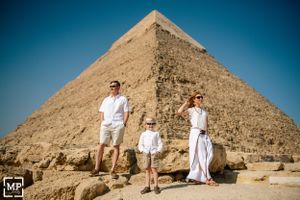 A family dressed in white stands together with the Great Pyramid of Giza in the background.