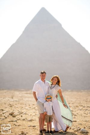A family poses together in front of the iconic Great Pyramid of Giza in Egypt's desert landscape.