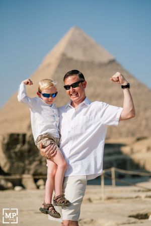Two people pose with flexed arms in front of the Great Pyramid of Giza in Egypt.