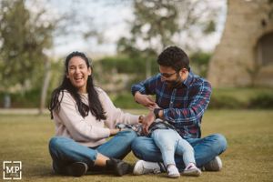 Couple sits on grass laughing together during an outdoor photoshoot.