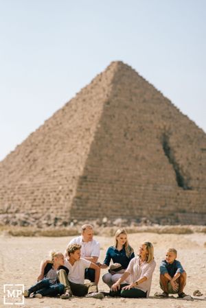 Tourists sitting together in front of Great Pyramid of Giza in Egyptian desert.