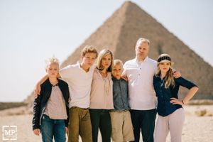 Group photo of tourists posing together in front of Egyptian pyramid.