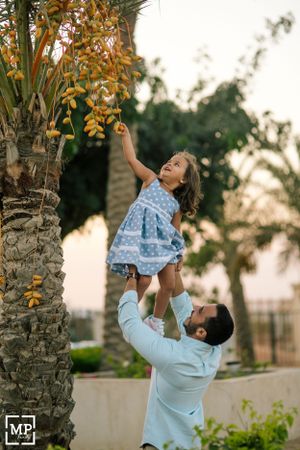 Playful moment captured near a palm tree during sunset.