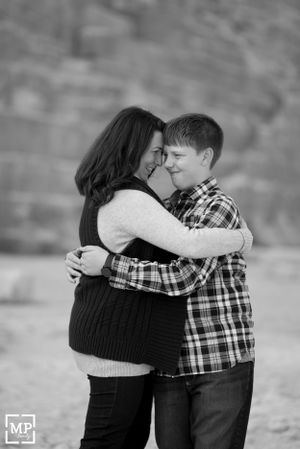 A tender black and white portrait showing an intimate embrace against a blurred background.