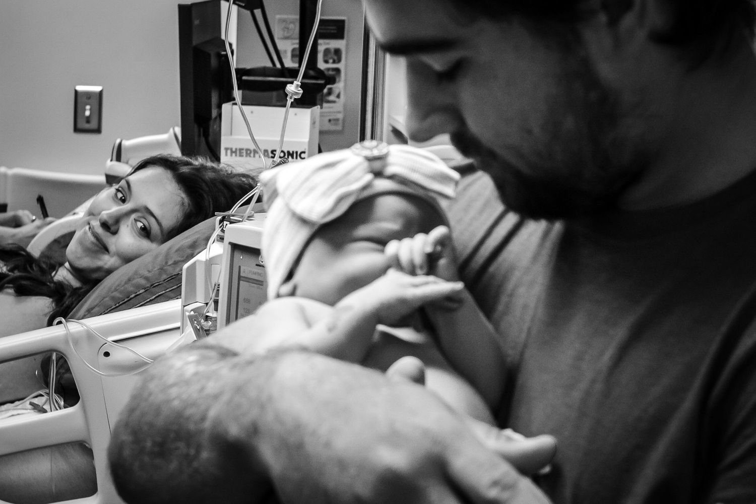 Mom looking on as her husband holds their baby girl for the first time just after birth in Sioux City, IA.