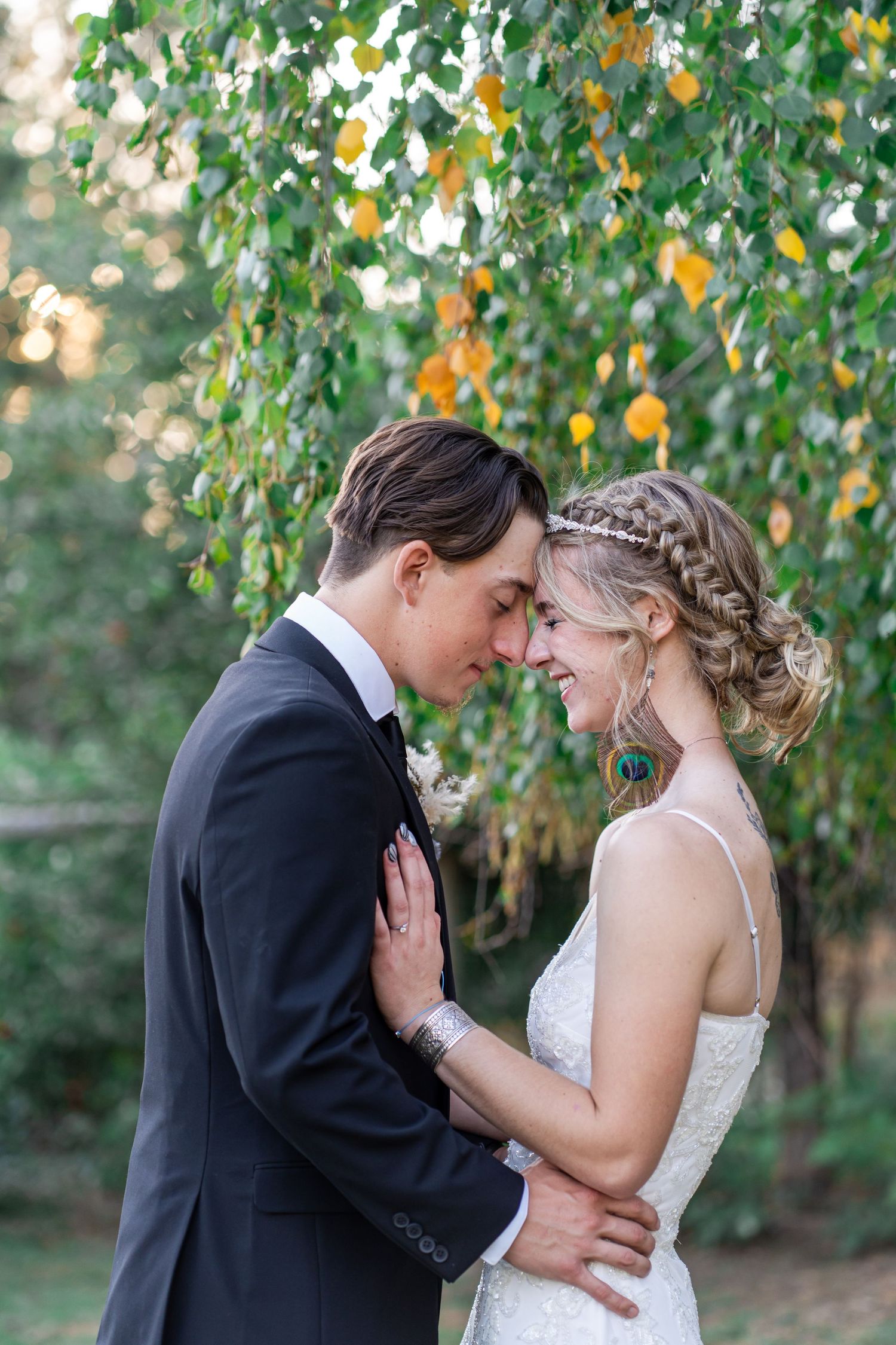 bride and groom share a moment by a tree
