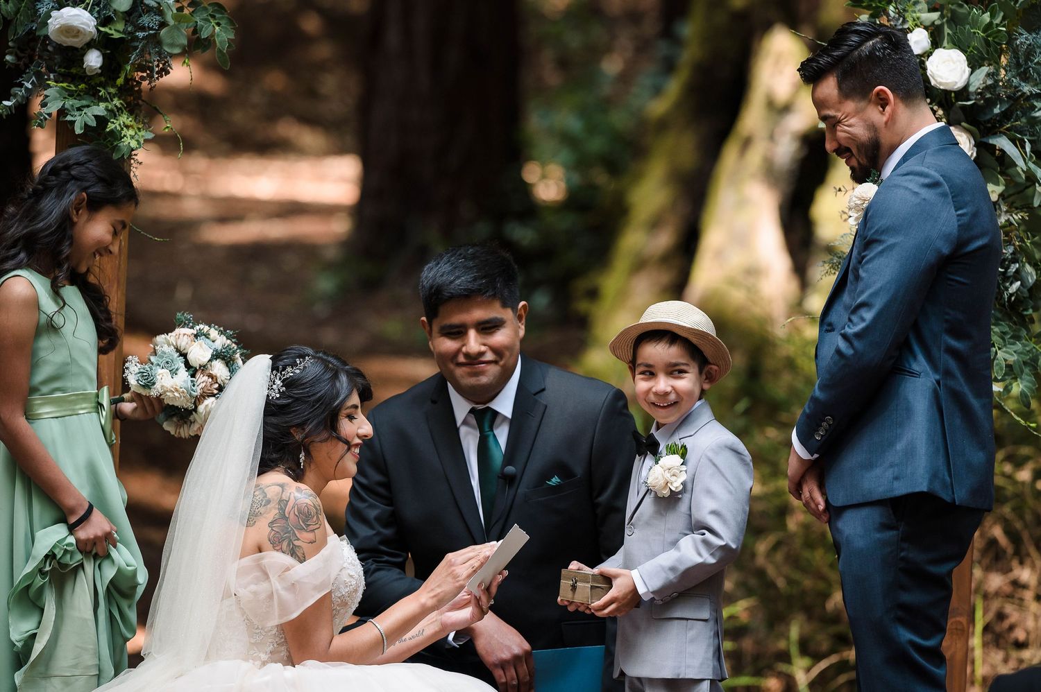 A heartwarming wedding ceremony moment unfolds beneath tall redwood trees.