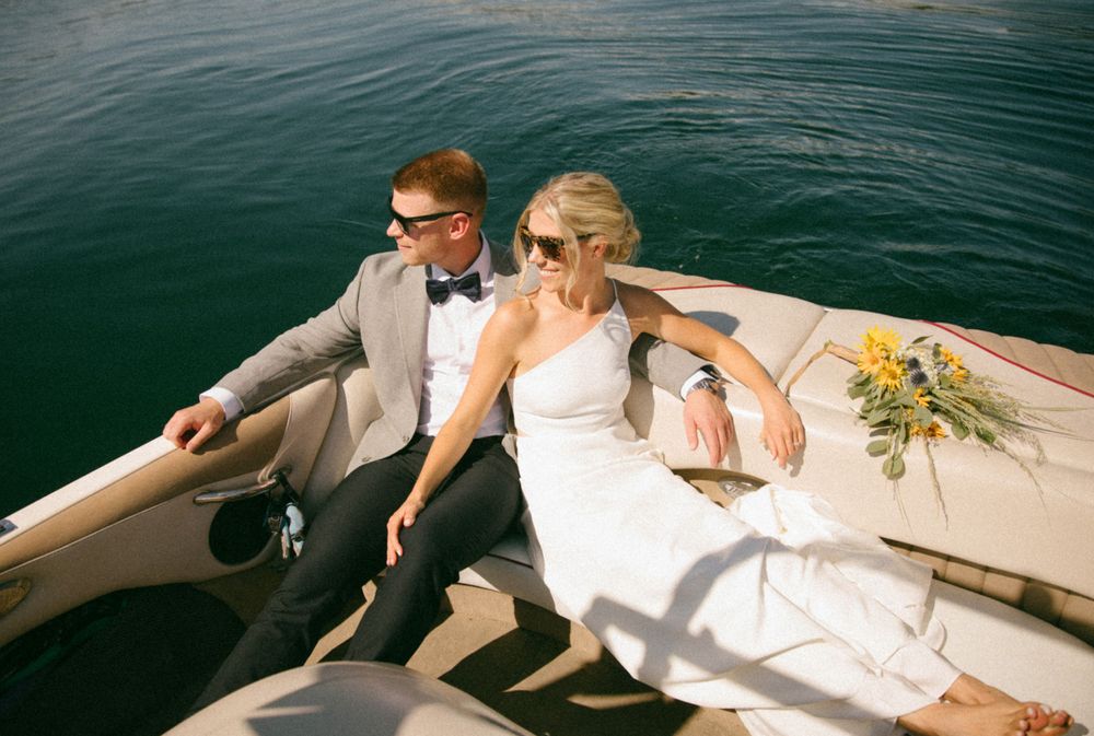 Newlyweds relaxing on a boat during their wedding day on calm waters.