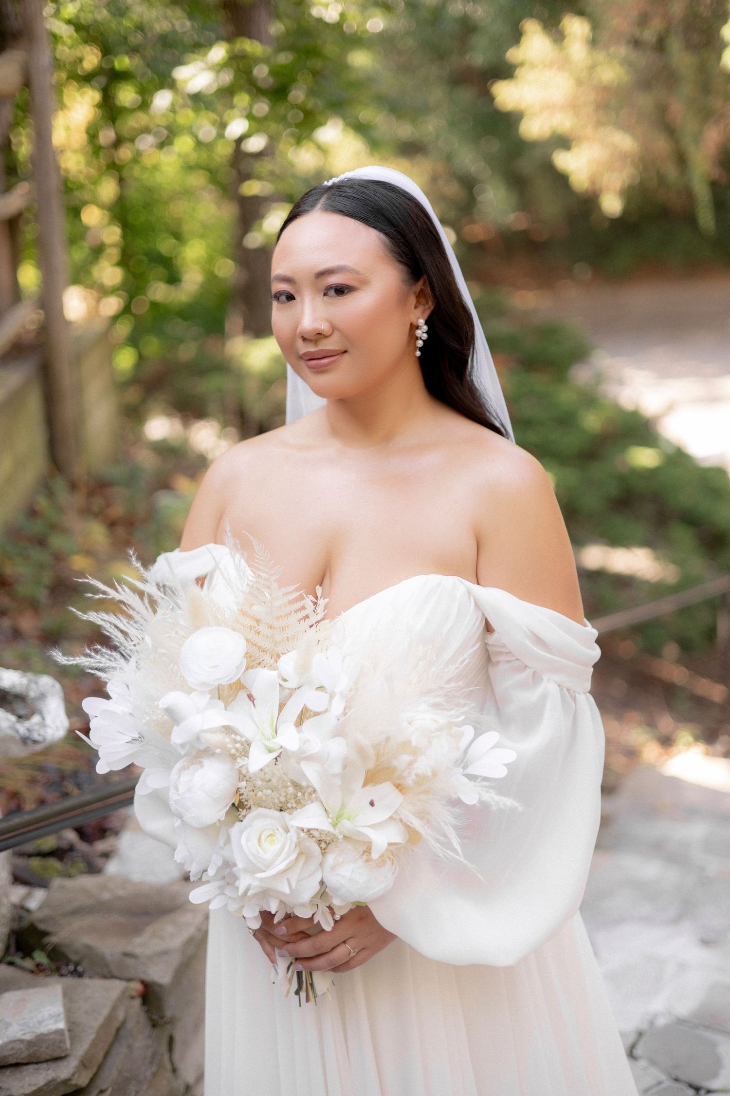 Bride holds elegant white and cream bouquet featuring roses and dried elements.