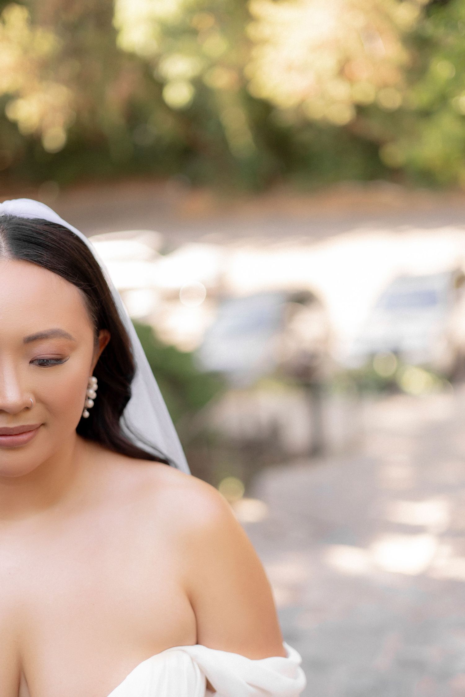 Soft portrait of a bride wearing pearl earrings and off-shoulder wedding gown.