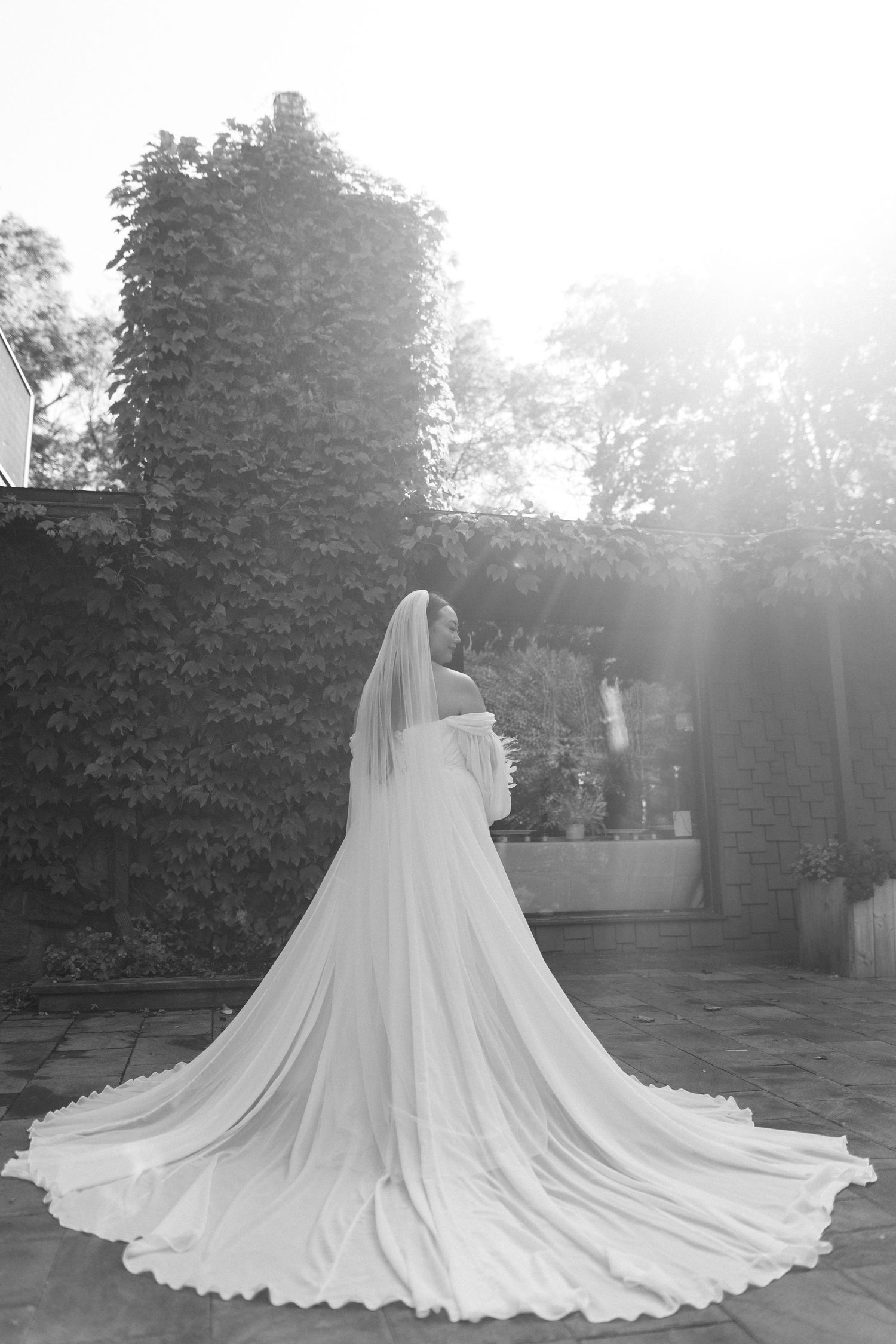 Dramatic black and white photo of bride in flowing cathedral length veil and train.