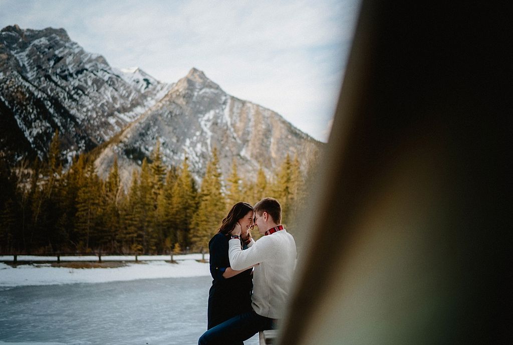 Intimate moment captured through natural frame with mountain peaks in background.
