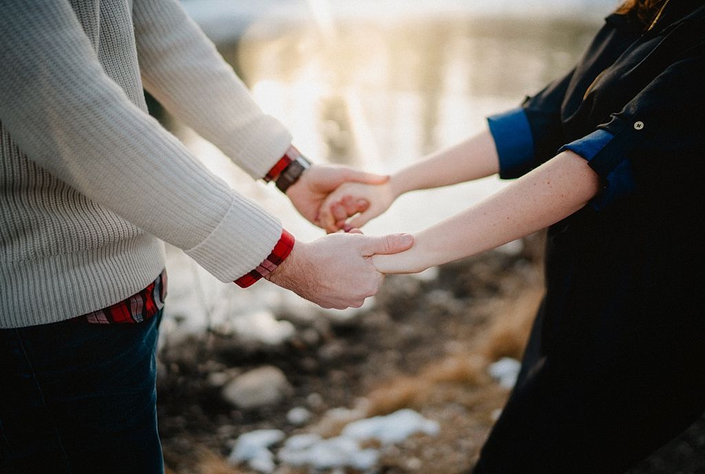Close-up of hands holding in romantic winter mountain setting.