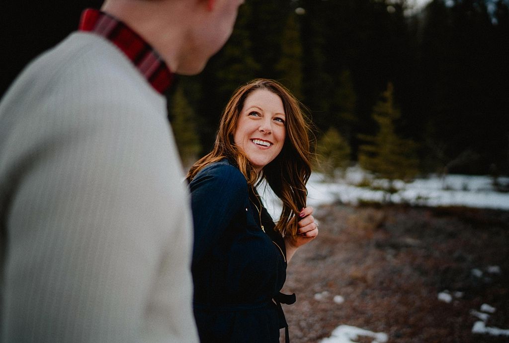 Joyful winter scene with couple sharing laughter against snowy mountain backdrop.