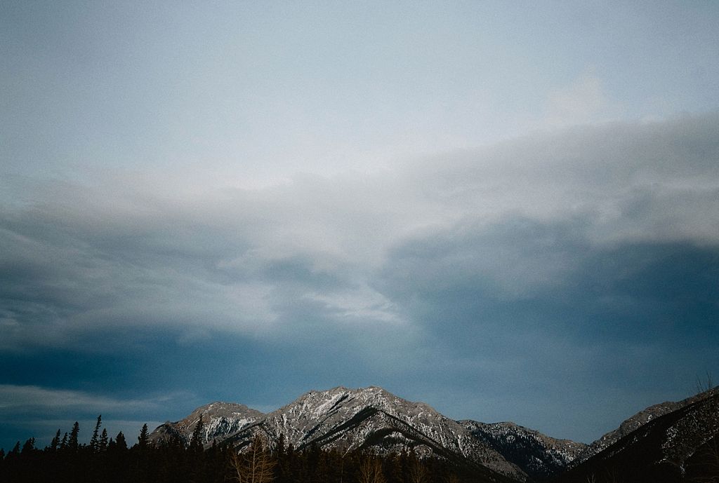 Dramatic mountain peak under moody blue sky in winter landscape.