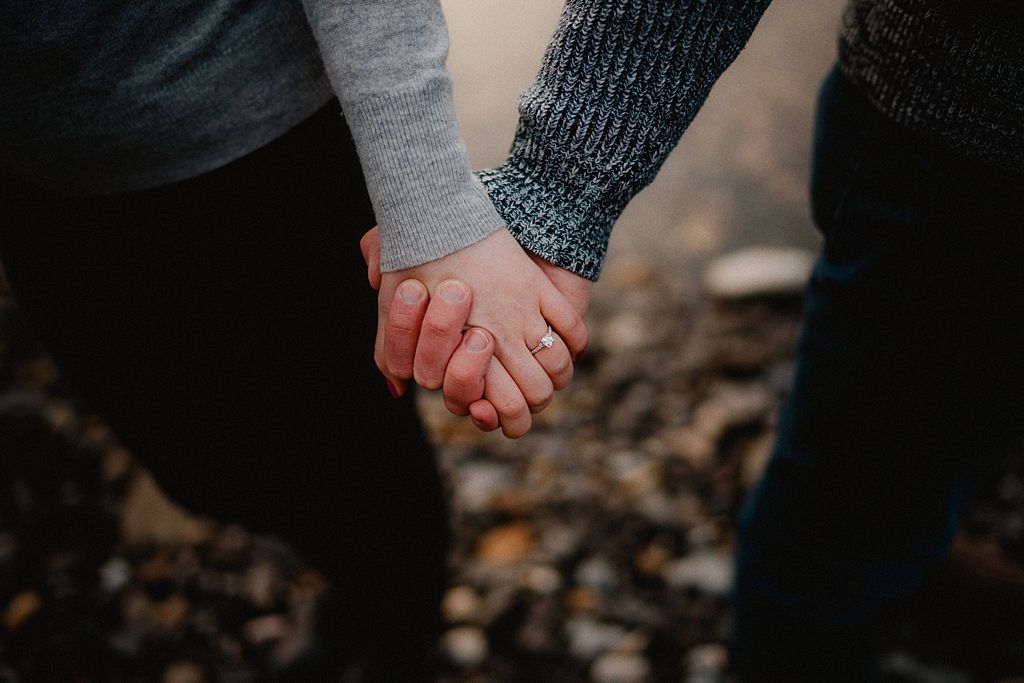 Close-up of two people holding hands while wearing warm winter sweaters.