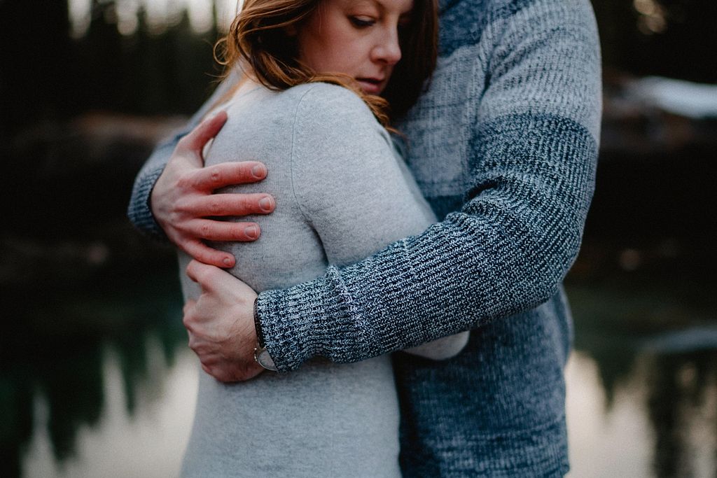 An intimate embrace captured in soft lighting with a grey sweater and knit texture in focus.