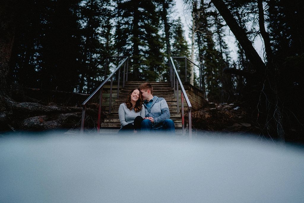 A romantic forest photoshoot with pine trees and snow creating a dreamy winter atmosphere.