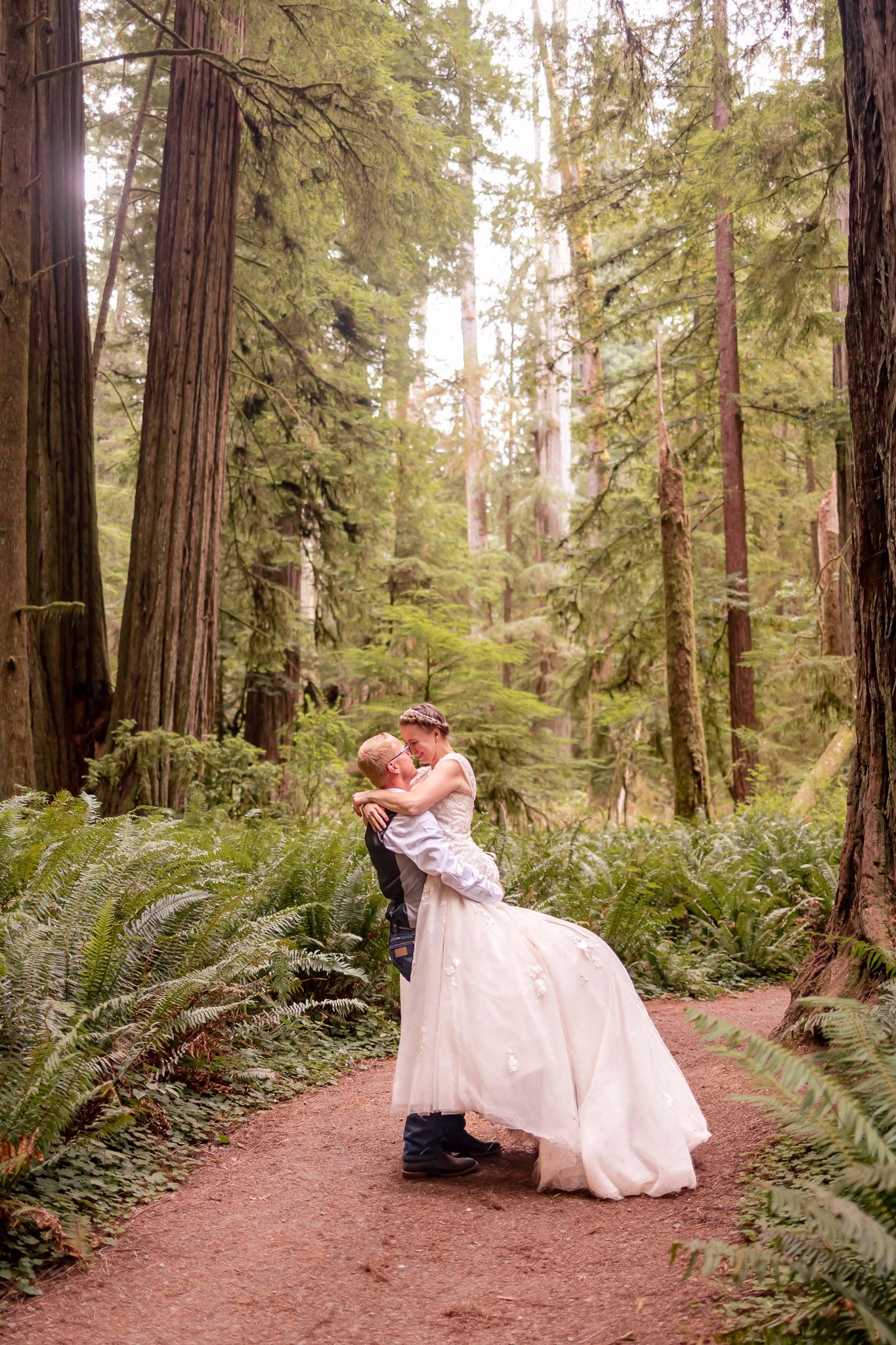 Groom lovingly picking up his bride while having pictures taken by Taylor Carpenter Photography in at the Jedediah Smith National Park