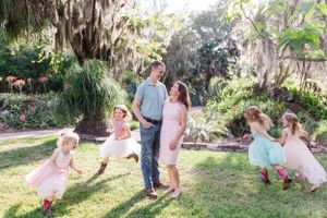 Family playing and laughing together in a lush backyard garden setting.