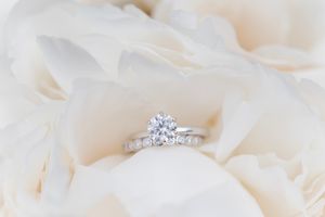 Close up of a sparkling diamond engagement ring nestled in soft white fabric.